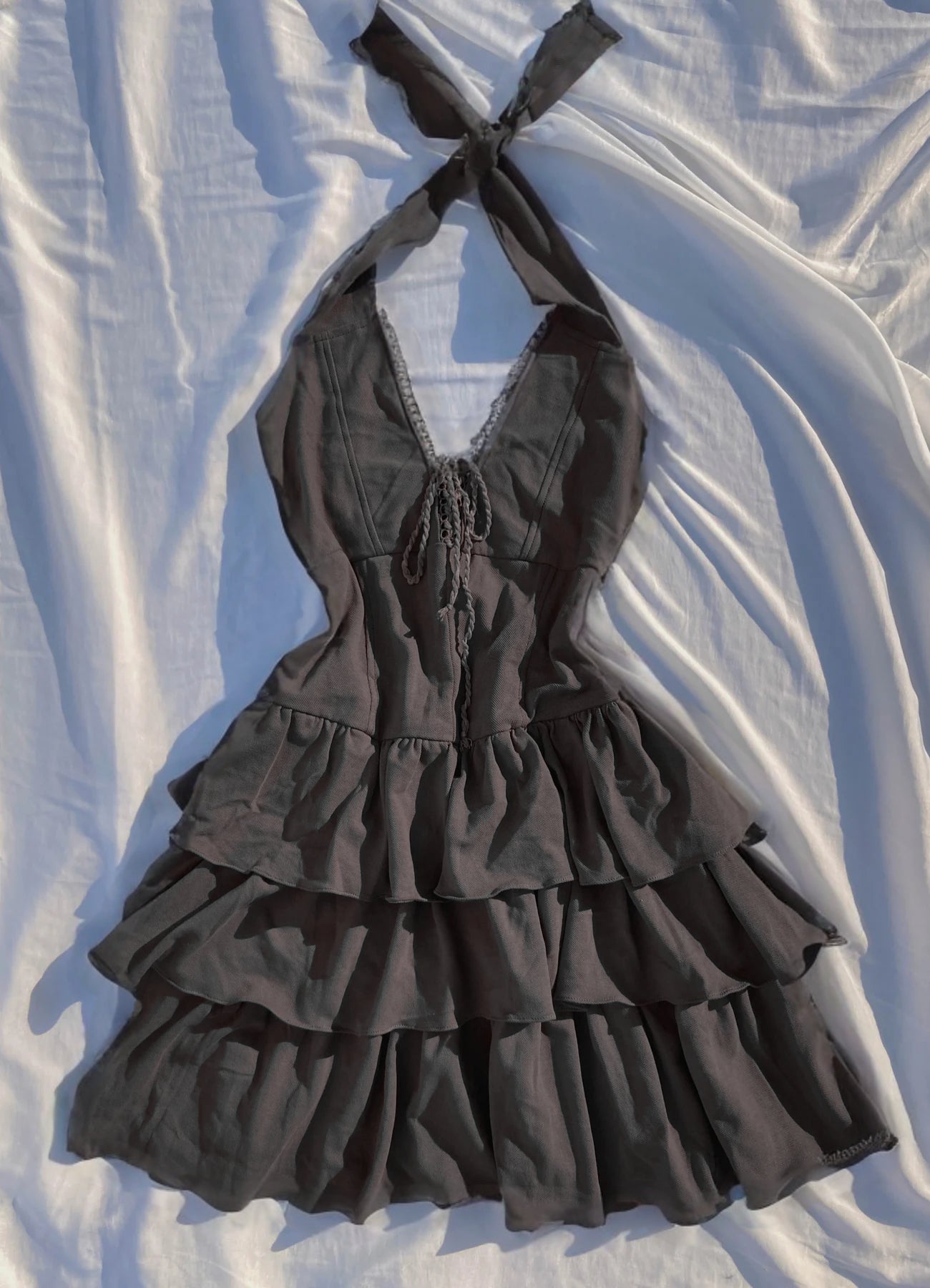 A green and black mini dress with a halter neck, lace-up front, and layered ruffles, displayed on a white background.